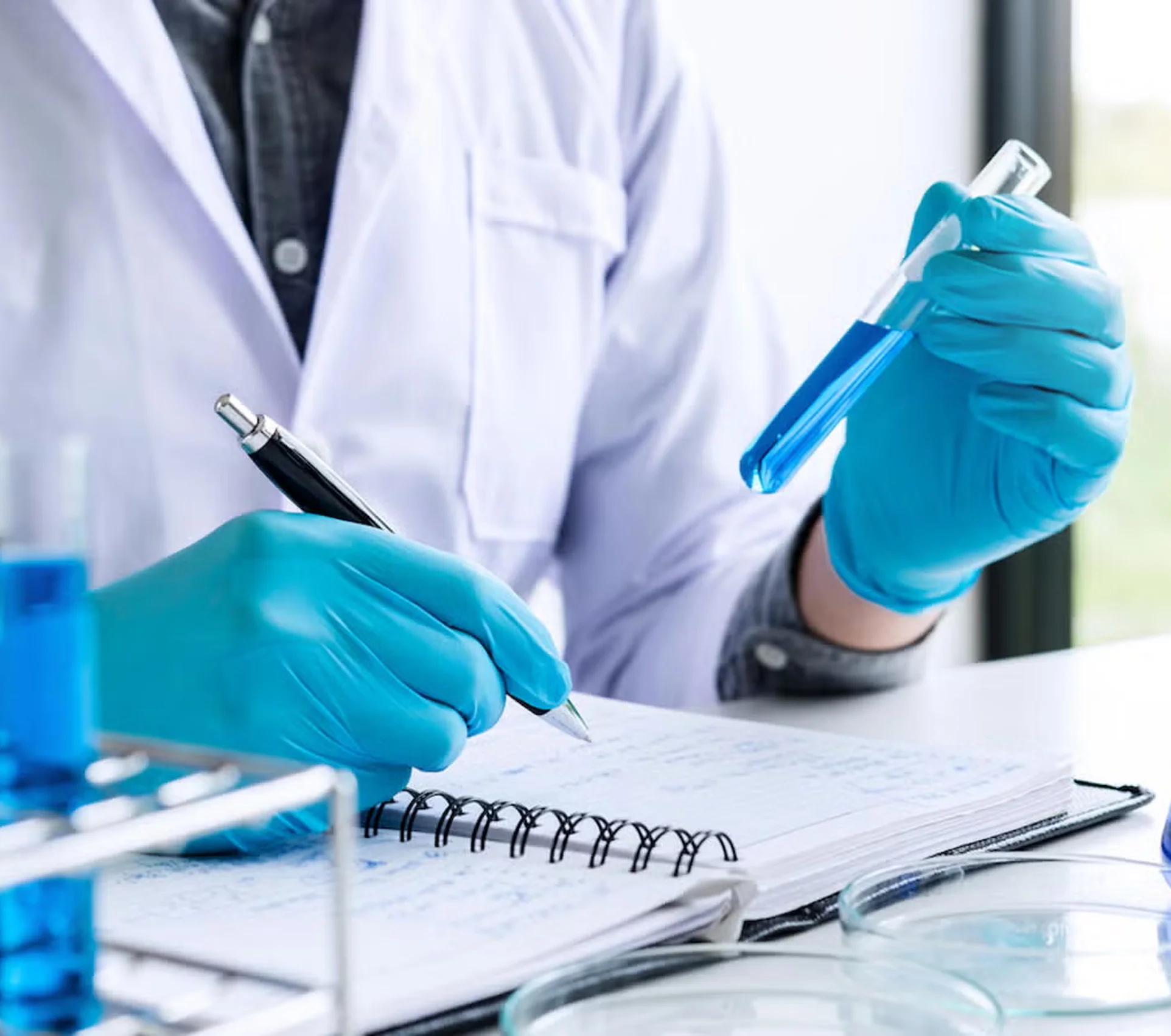 Chemist taking notes while holding a test tube of blue solution